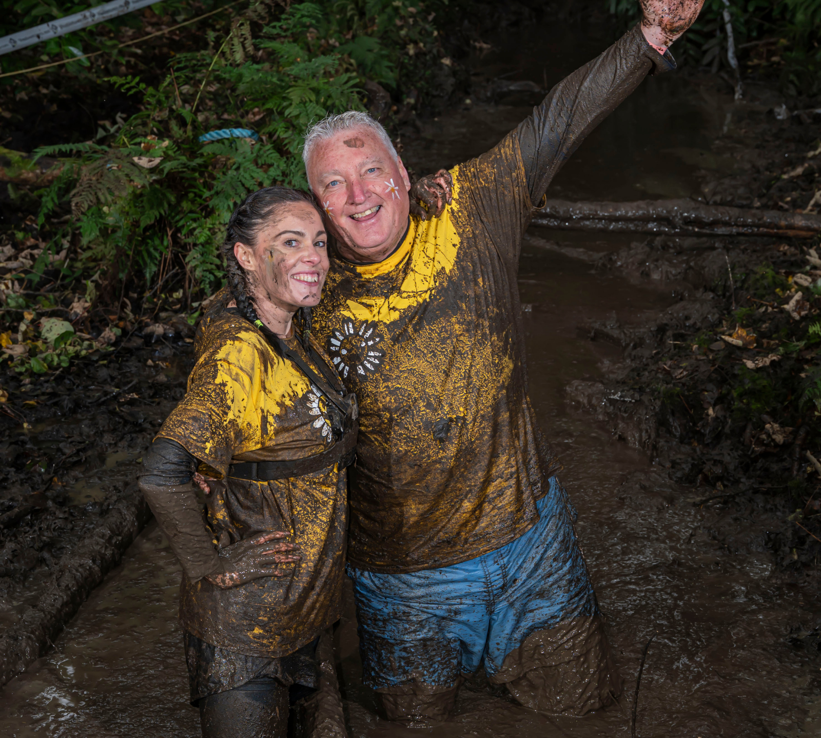 2 runners posing for a photo in a mud pit for the 2025 event
